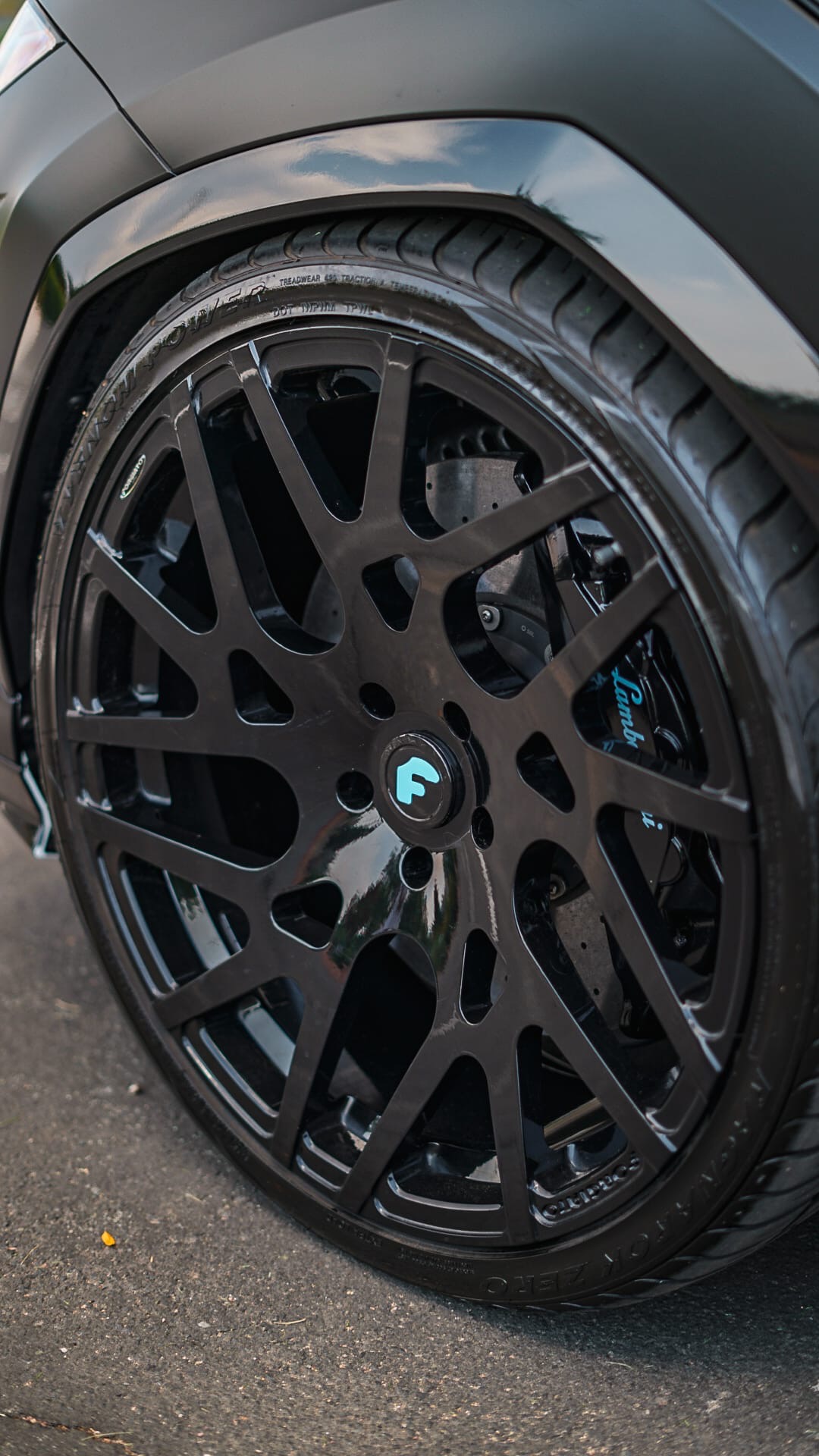 Close-up of black Forgiato wheel with teal center cap on Urus