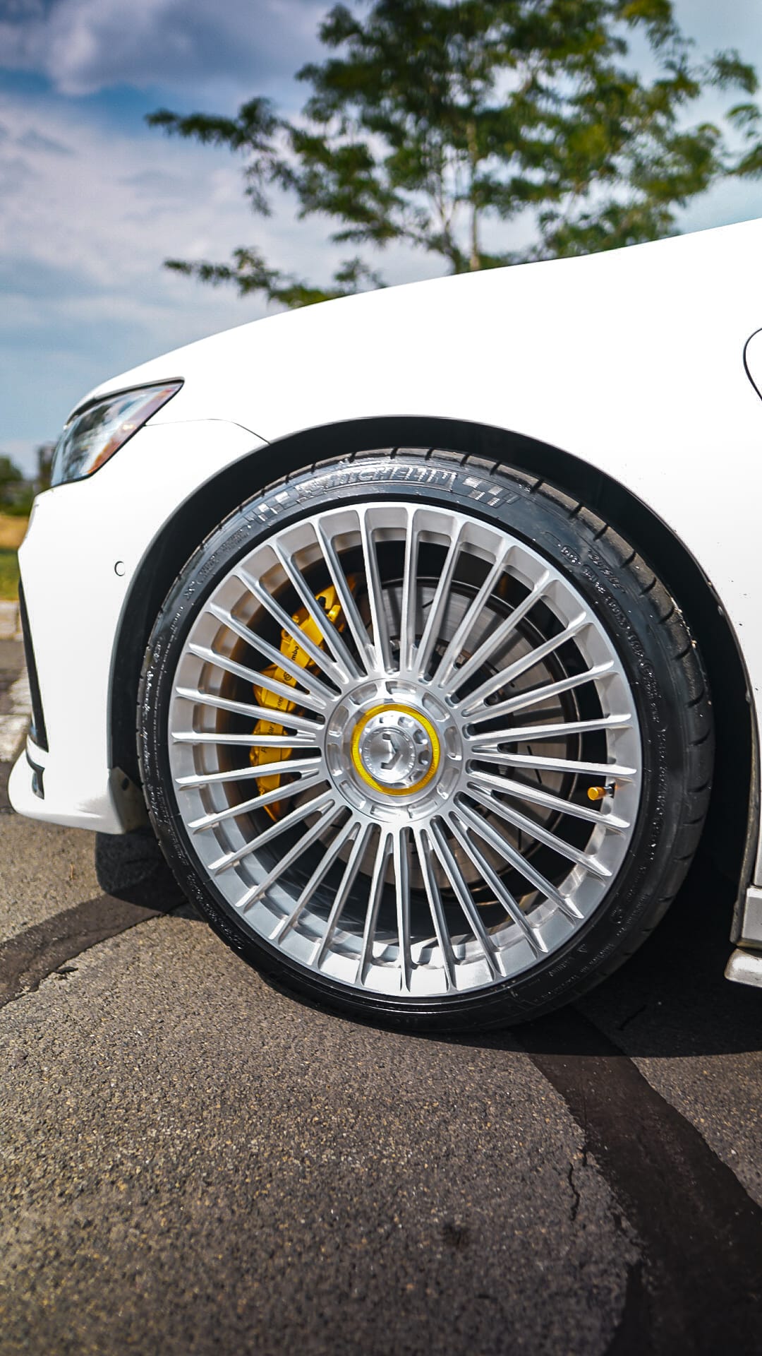 Polished multi-spoke wheel on white Volvo with yellow brake caliper