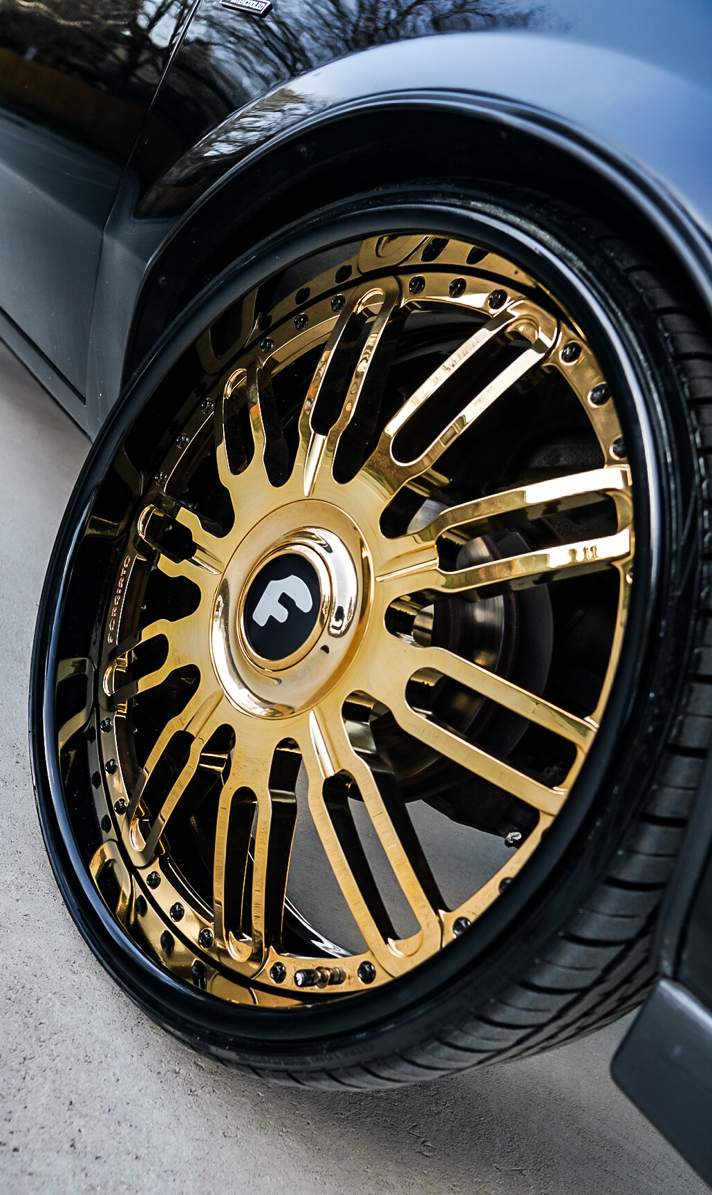 Close-up of polished gold Forgiato multi-spoke wheel on Buick Grand National