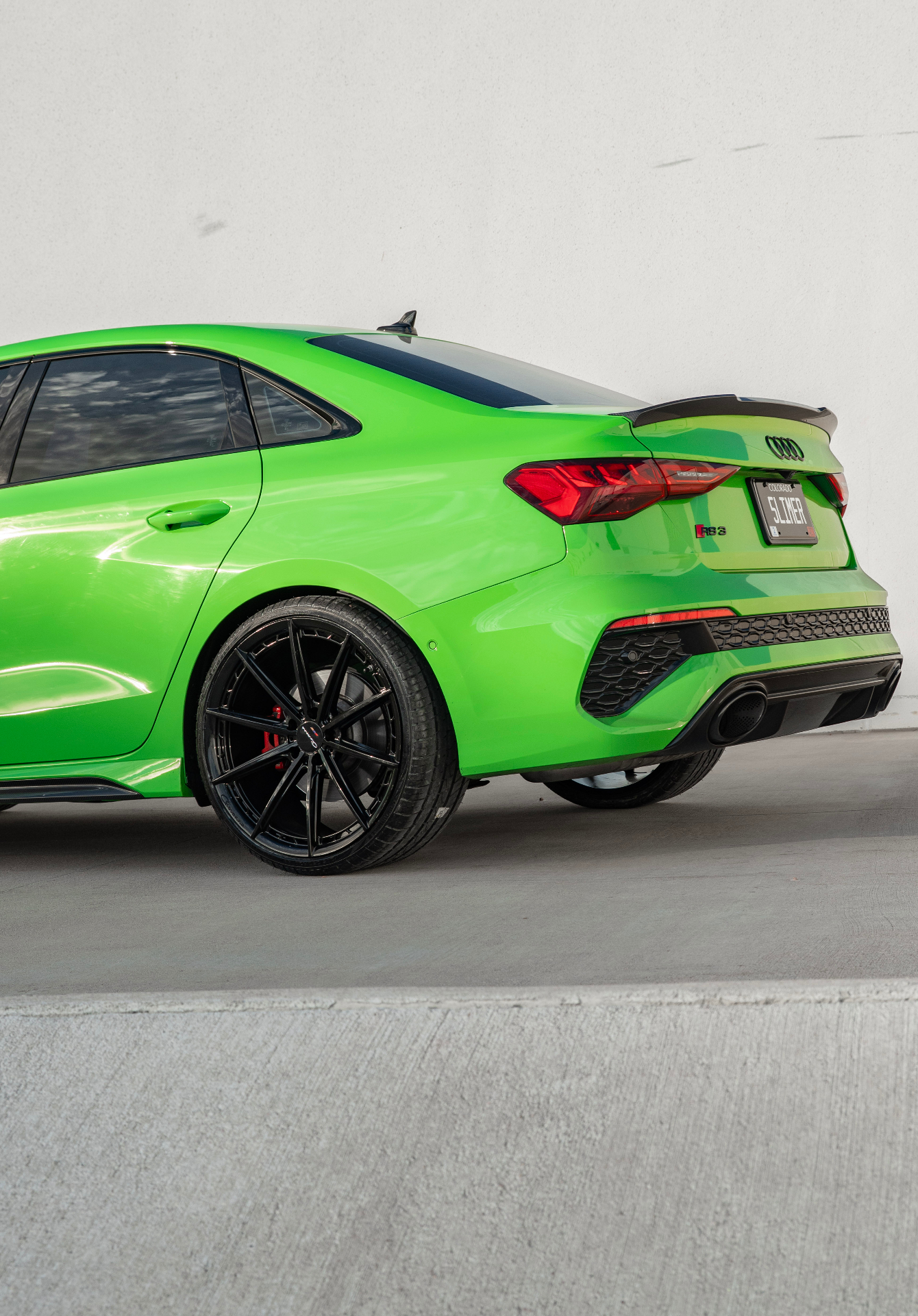 Rear three-quarter detail of lime green Audi RS3 with SLIMER plate