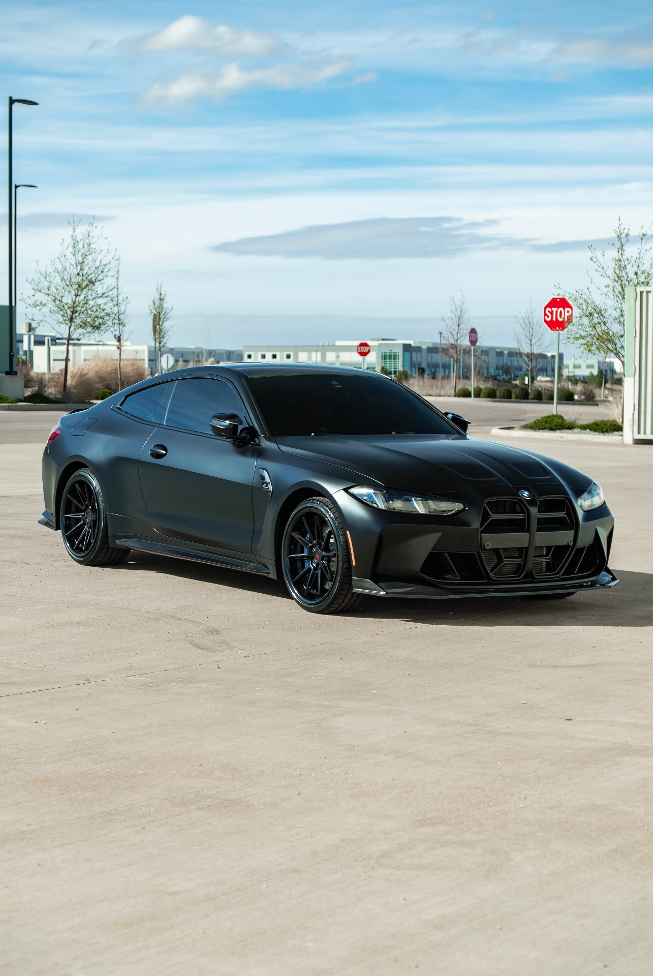 Matte black BMW coupe parked outdoors on large black custom wheels