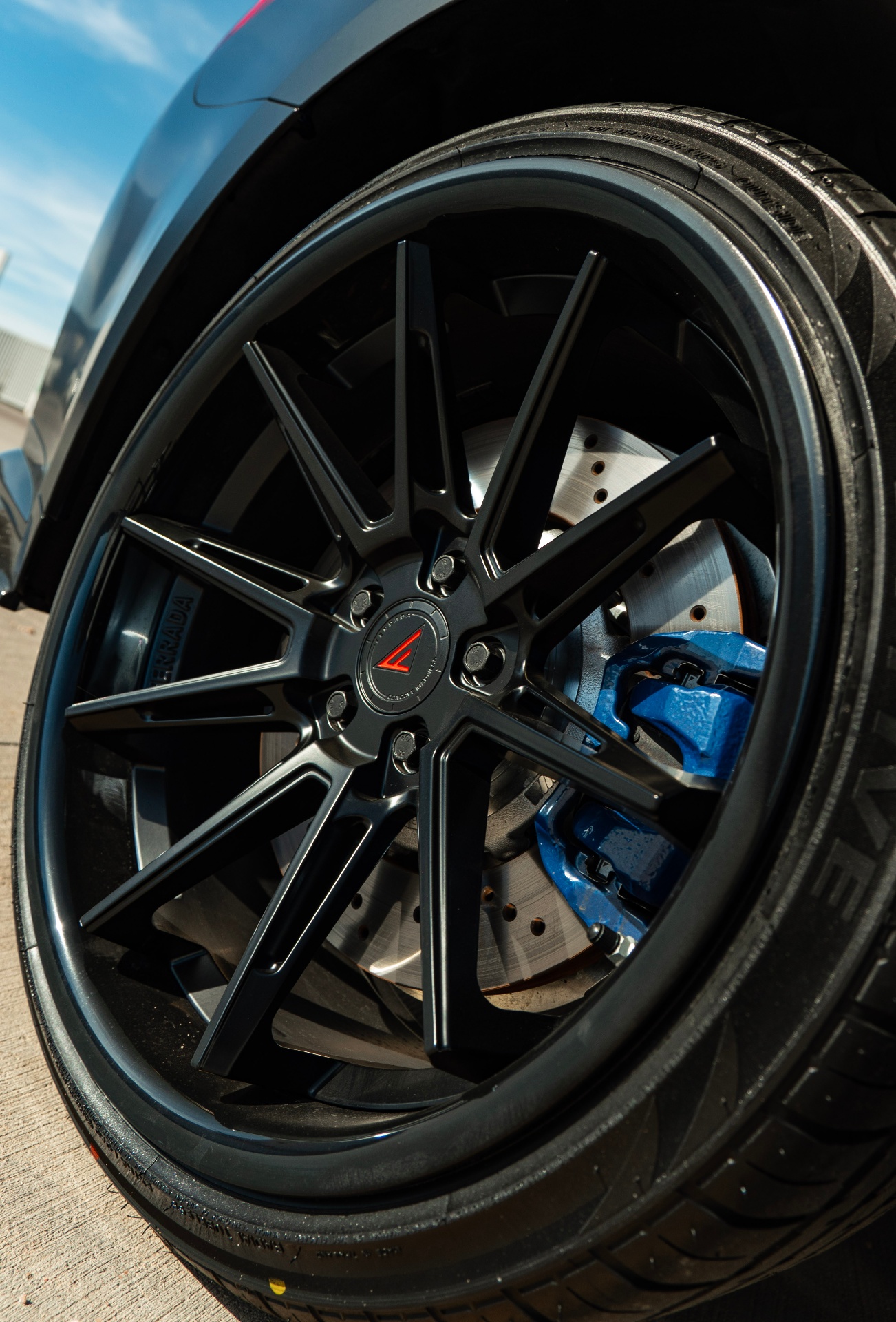 Close-up of black multi-spoke wheel with blue brake caliper on BMW