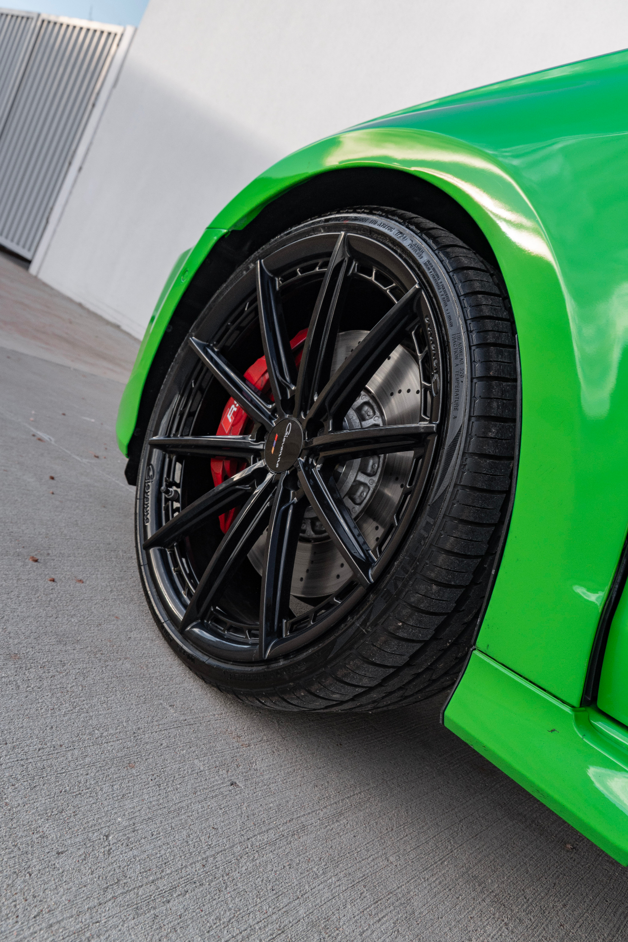 Close-up of black Giovanna wheel and red caliper on lime green Audi RS3