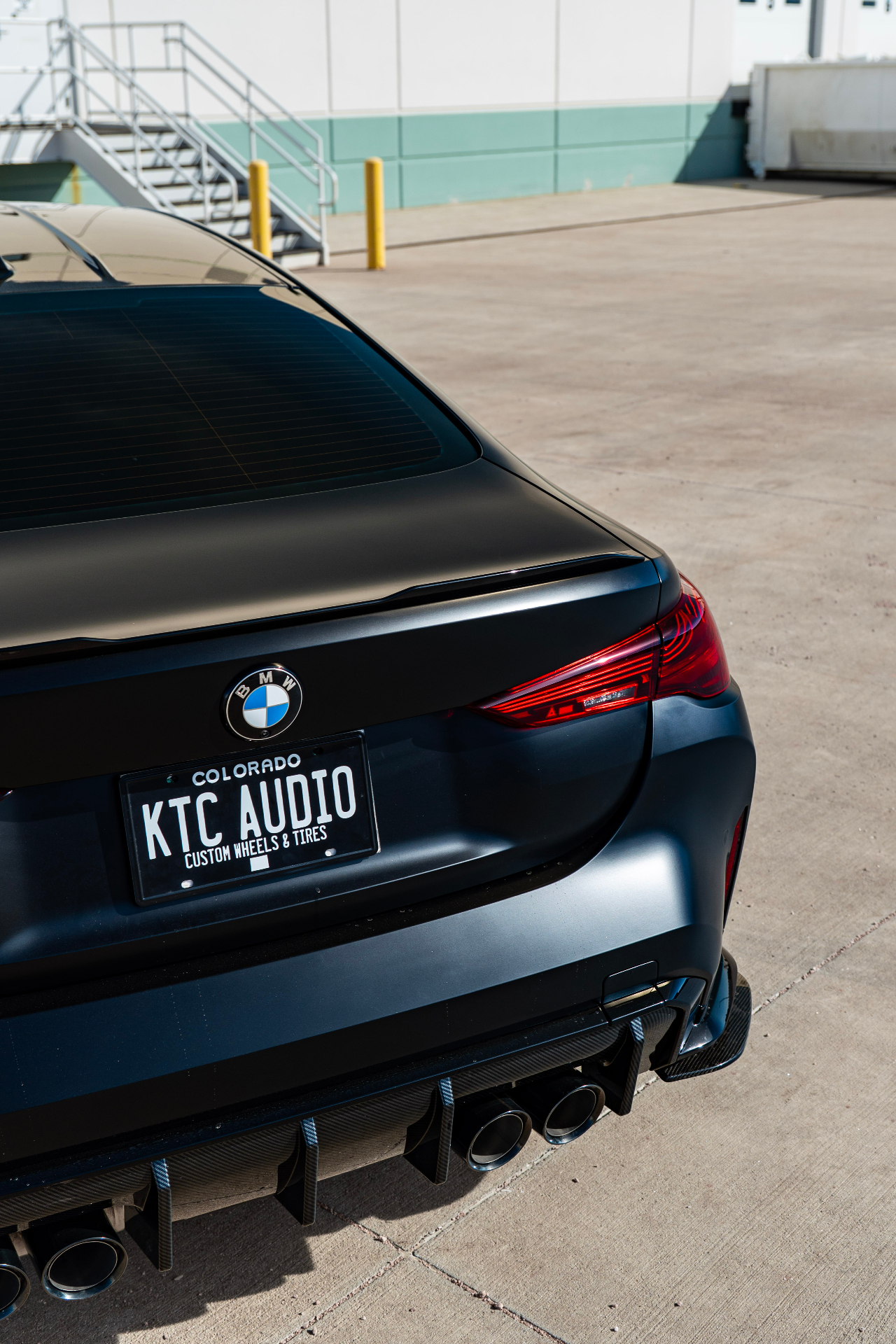 Rear three-quarter detail of matte black BMW with KTC Audio plate