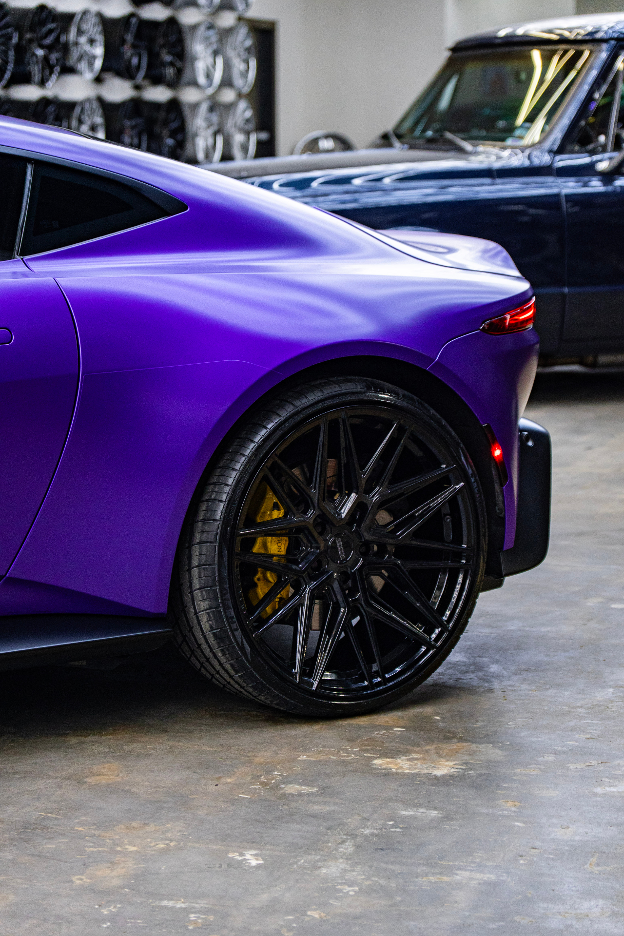Close-up of the rear quarter and black wheel on a satin purple Aston Martin Vantage