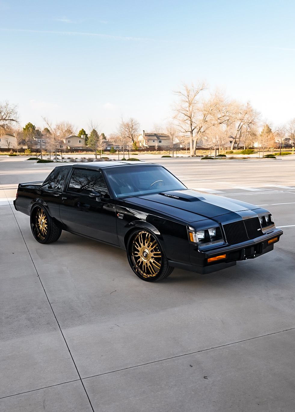 Blacked-out Buick Grand National 3.8 SFI Turbo on gold Forgiato wheels in an empty lot
