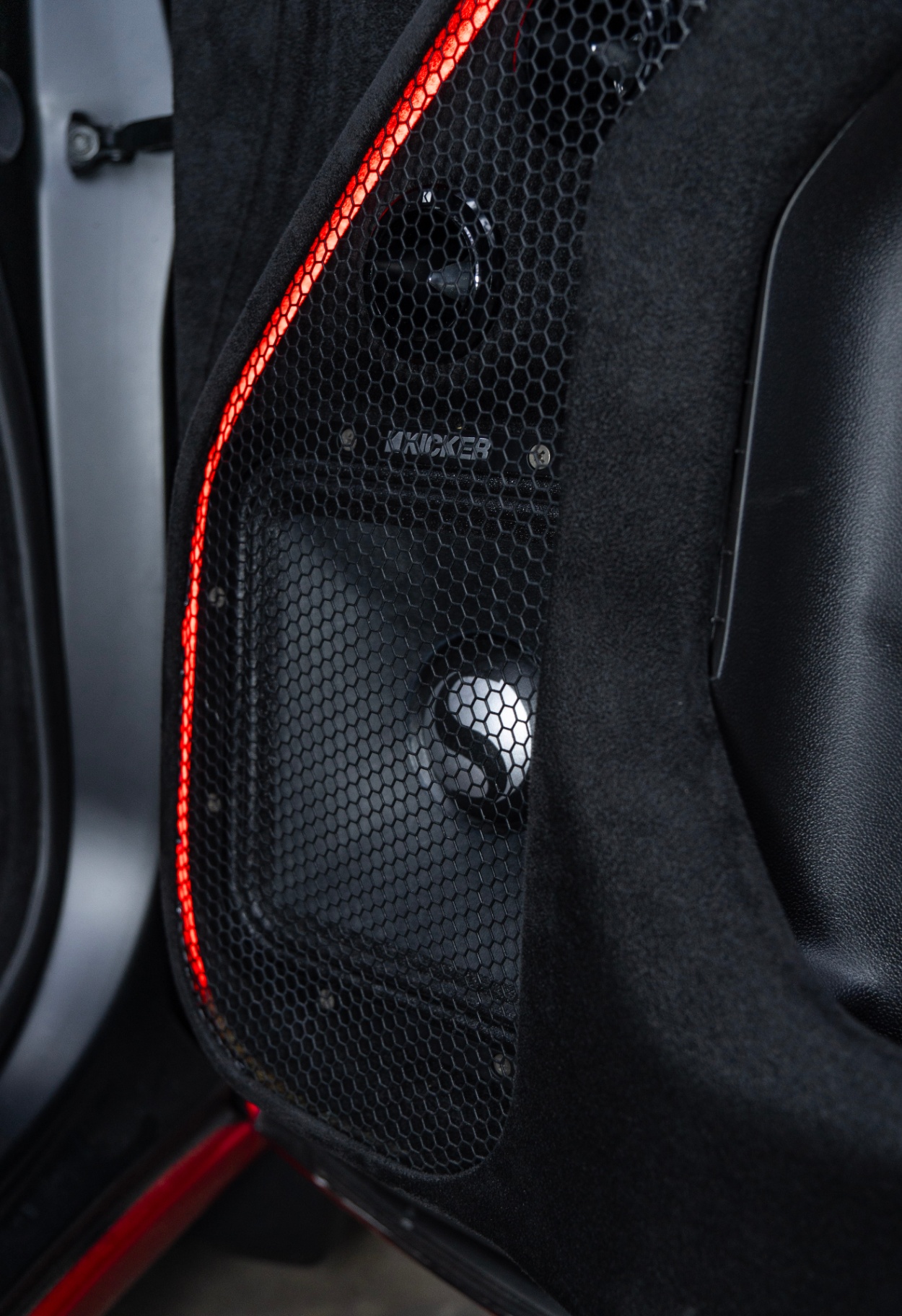 Custom GMC door panel with Kicker speakers behind black mesh and red LED trim