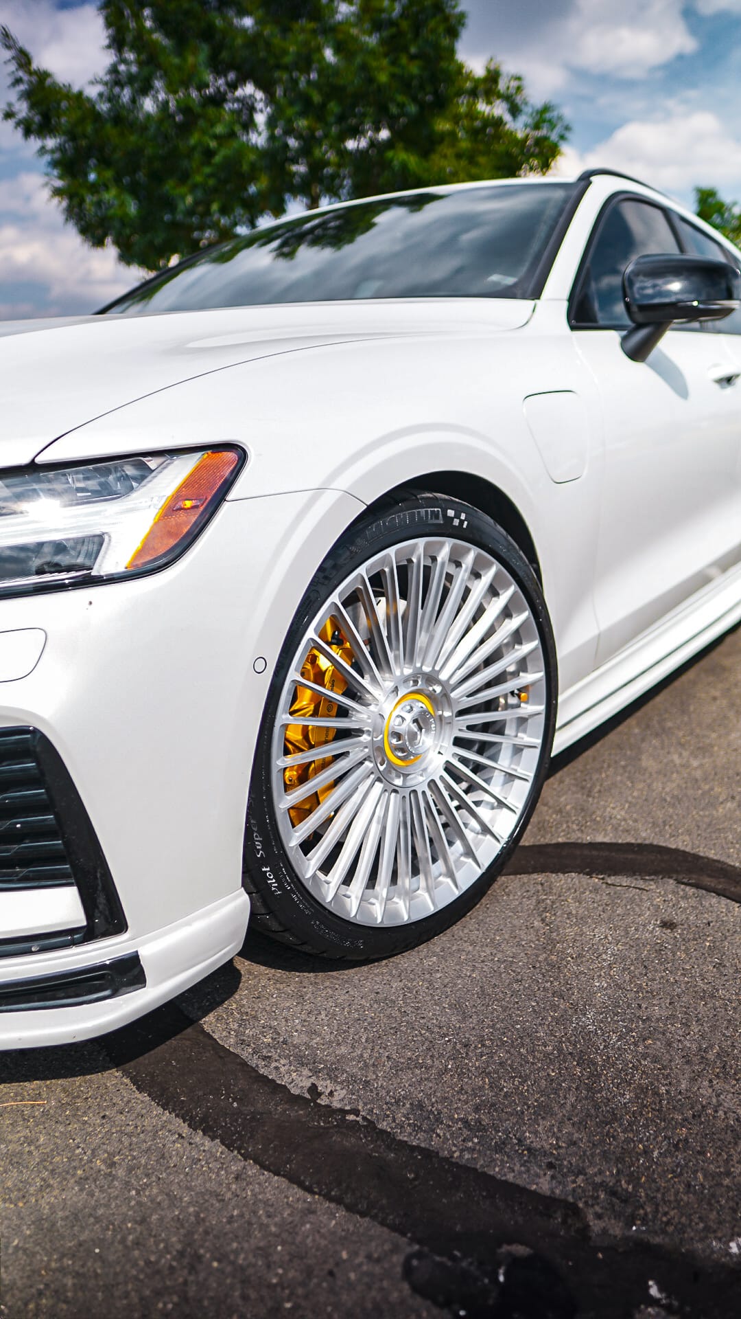 White Volvo V60 front fitment on polished turbine-spoke wheels