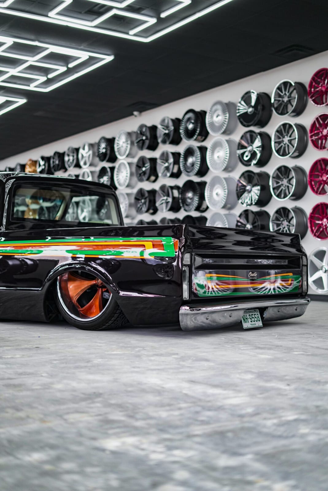 Custom black C10 pickup bagged on the floor in front of KTC wheel wall